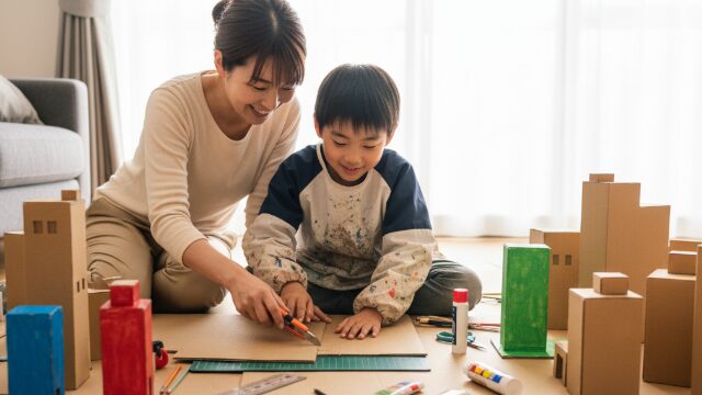 大きな板ダンボールを使って、楽しそうに何かを制作している親子